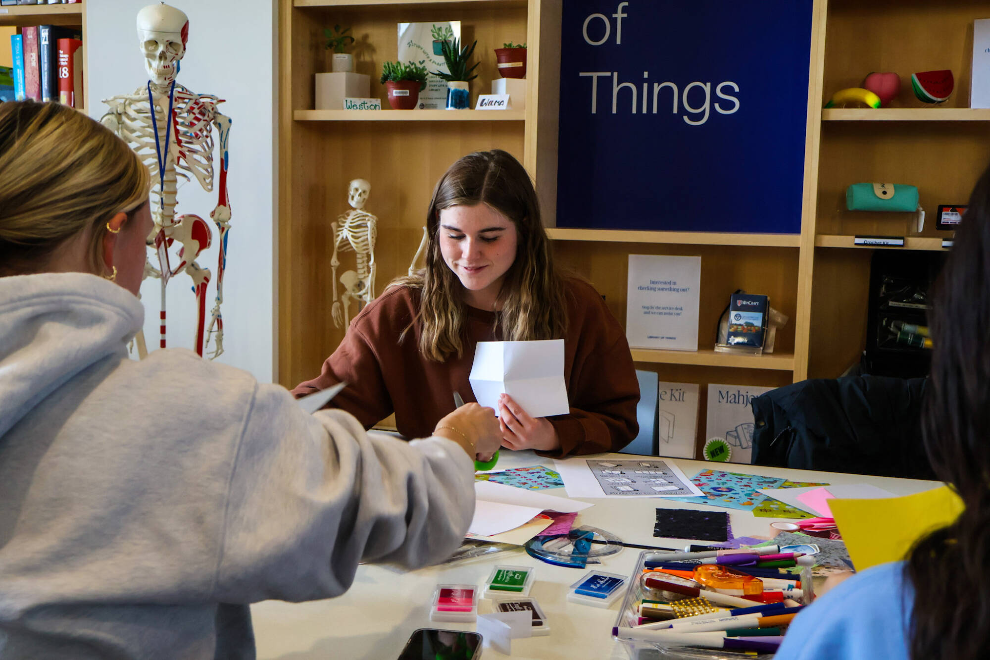 Emily Shaner works on finding the perfect materials to create her Zine while chatting with other students at her table.Photo Release on file